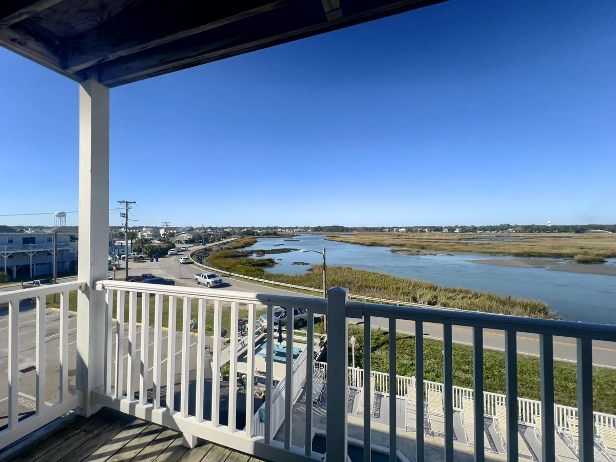 A scenic view of the nearby river and marshland, framed by distant buildings and a roadway. The tranquil setting highlights the natural beauty surrounding Cherry Grove, offering glimpses of water, greenery, and open air—an invitation to explore beyond the villa itself.